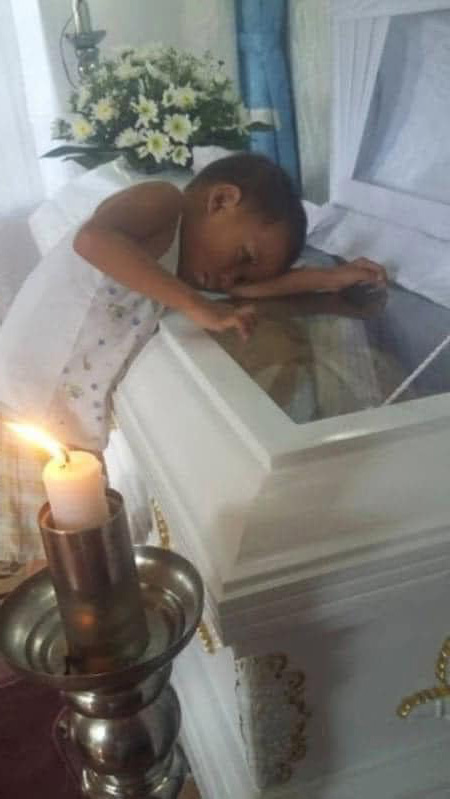 Boy hugs his mother’s coffin